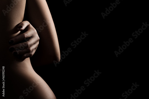 female embraced herself back on black background with copy space