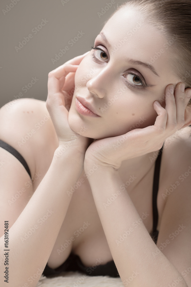 Naklejka premium sensual beautiful girl lying on white fur, looking at camera