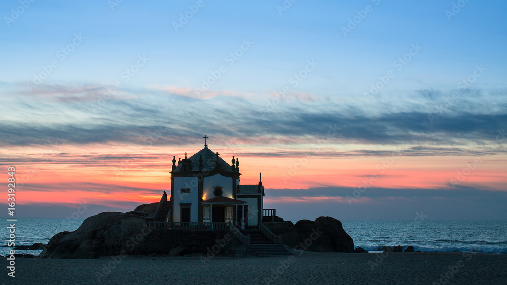 Chapel Senhor da Pedra at Miramar Beach at night time, Atlantic ocean, Porto, Portugal.