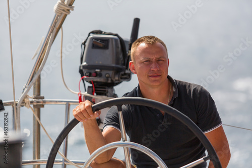 A young skipper at the helm of a sailing ship.