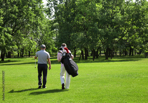 Canvas-taulu Young men on golf course in sunny day