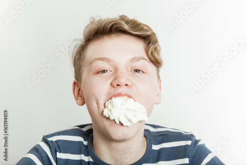 Boy goofing off as his mouth is stuffed with creme