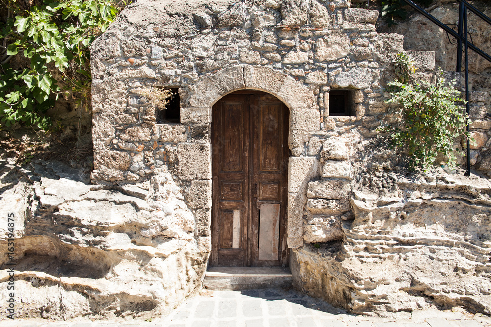 Old wooden door to a stone basement in a Greek house.