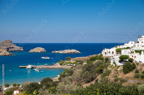 Typical Greek architecture. White houses on the coast.Fragment of the town lidos under acropolis. View of the harbor and bay. Blue sea lagoon and ships.
