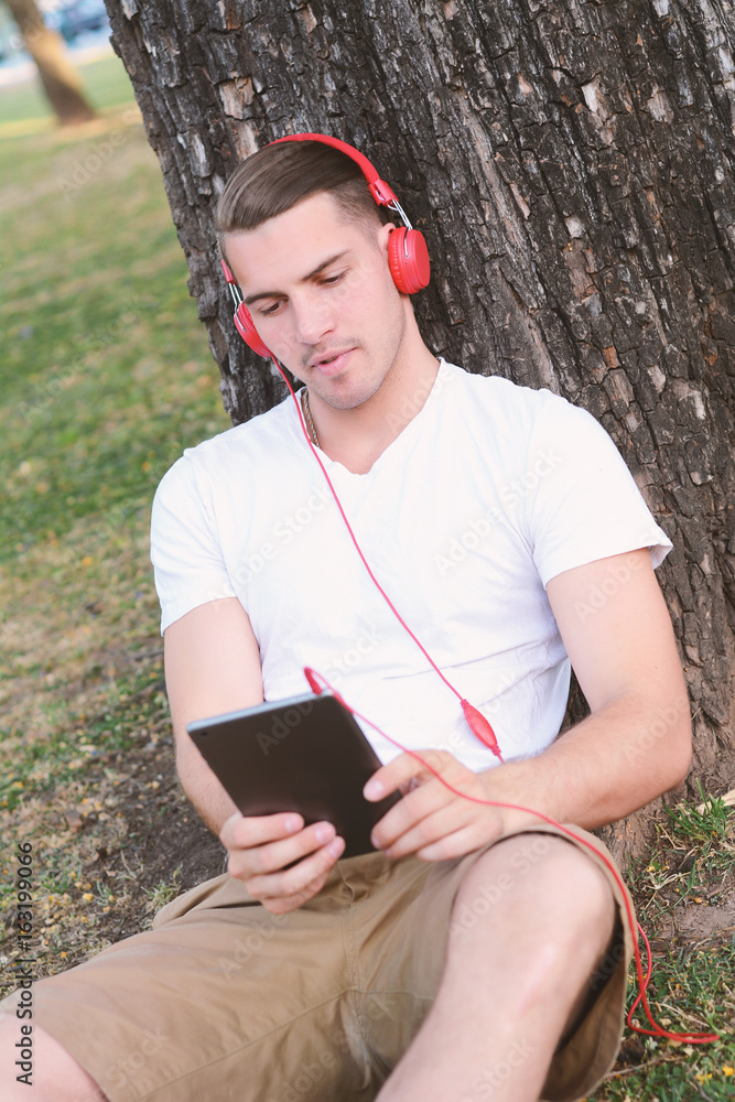 Fototapeta premium Young man with headphones, holding a tablet.