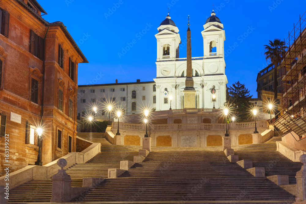 Monumental stairway Spanish Steps, seen from Piazza di Spagna, and Trinita dei Monti church during morning blue hour, Rome, Italy.