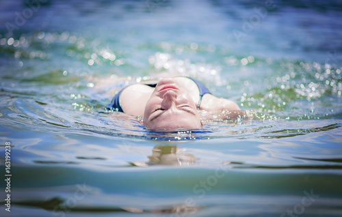 Attractive blonde woman swimming in the clear sea water on the beach