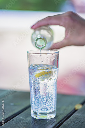 Hand pouring refreshing drink into a glass