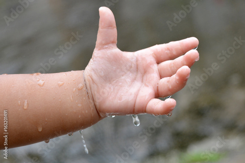 Child's hand is playing with rain drops © LintangDesign