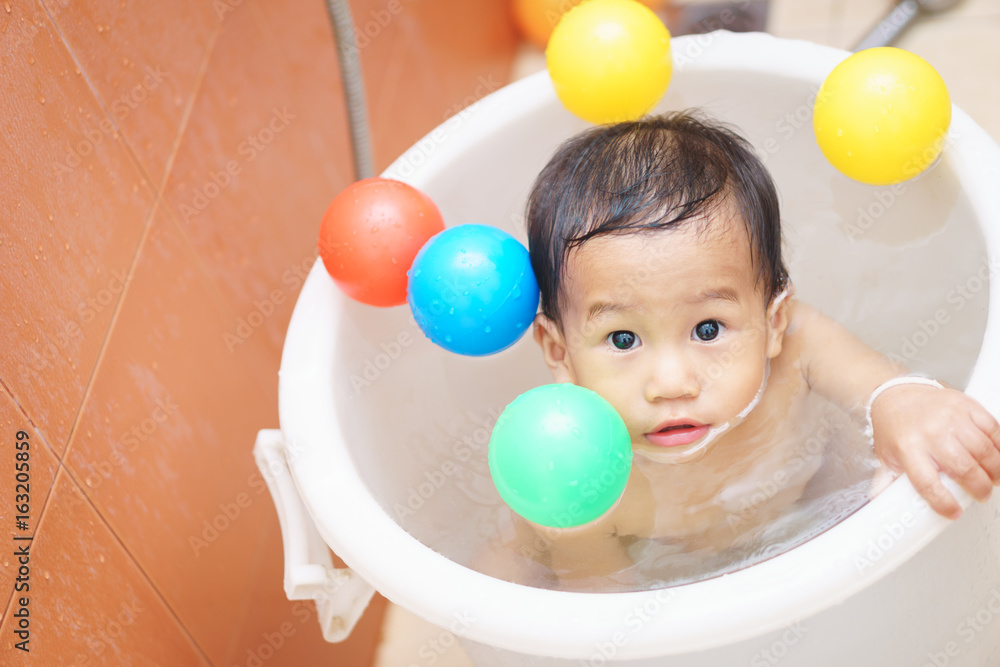 A year old and 5 months Asian baby play a ball while taking a shower A year old and 5 months Asian baby play a ball while taking a shower