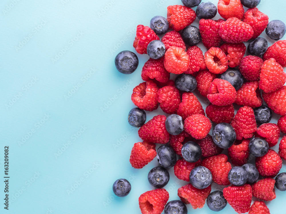 Raspberry and blueberry on blue background with copy space Raspberry and blueberry on blue background with copy space