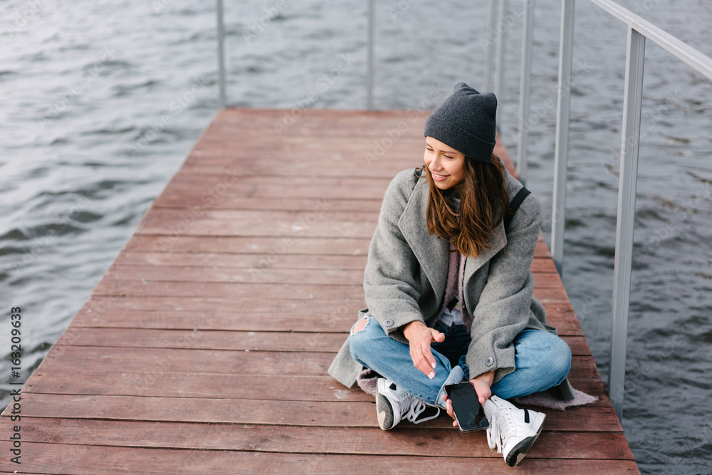 Young pretty girl on wooden bench on old pier Young pretty girl on wooden bench on old pier
