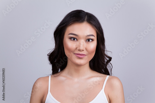 Portrait of a beautiful asian woman with makeup and light curls.