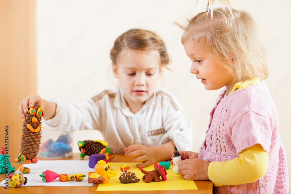 Naklejka premium Preschoolers molding figurines from plasticine