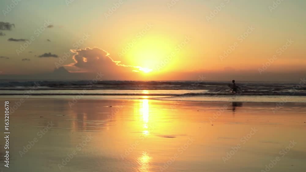 Sunset beach, small boy with surfboard going through waves Sunset beach, small boy with surfboard going through waves