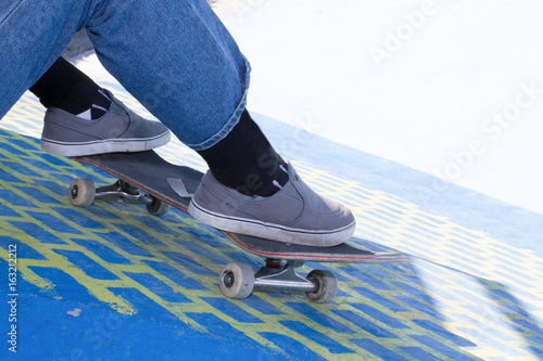 Closeup of teenager having break in a skate park on summer day outdoors side view Skater with skateboard sitting and chilling at urban area