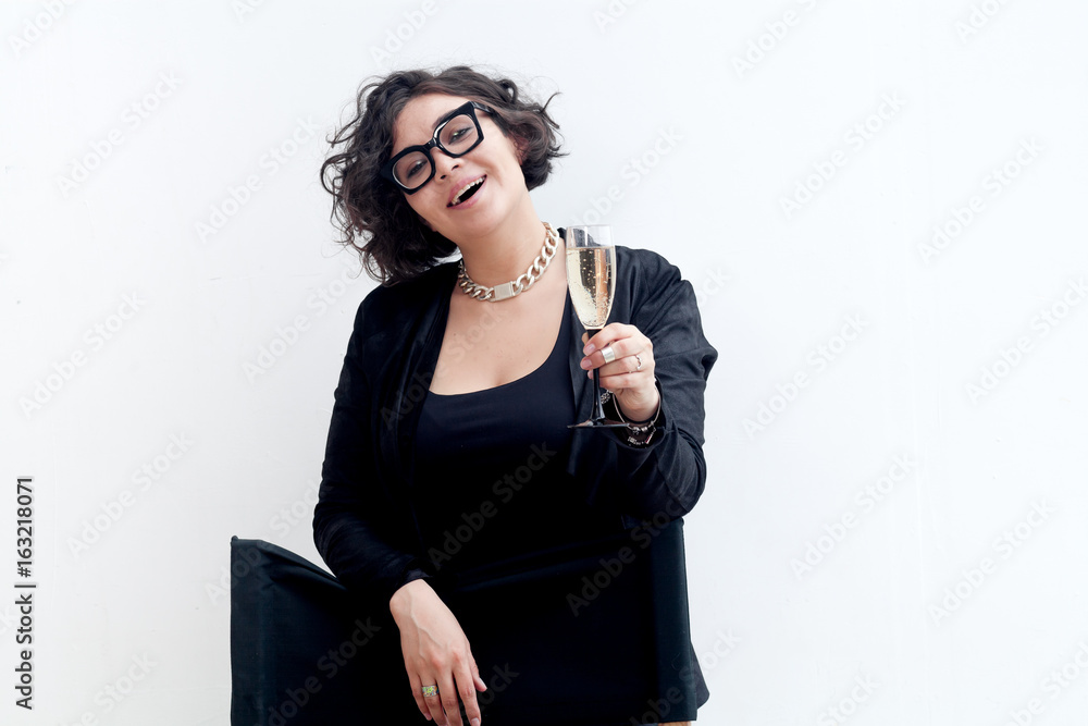 Portrait of young plus size model with fashionable glasses dressed in black holding a glass of champagne. Composition with copy space. Portrait of young plus size model with fashionable glasses dressed in black holding a glass of champagne. Composition with copy space.