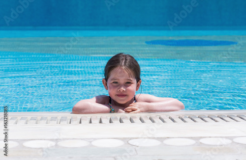 Happy little girl swimming in a pool