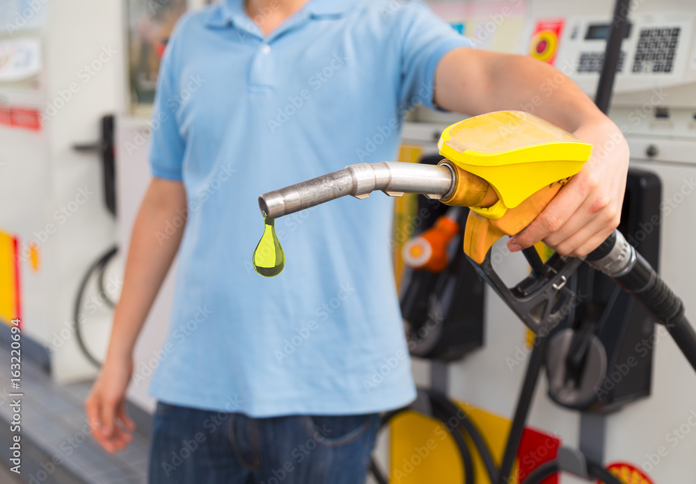 Man hold fuel nozzle to add fuel in car at gas station. Man hold fuel nozzle to add fuel in car at gas station.
