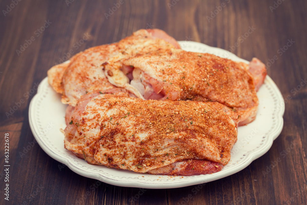 raw chicken with herbs  on white plate