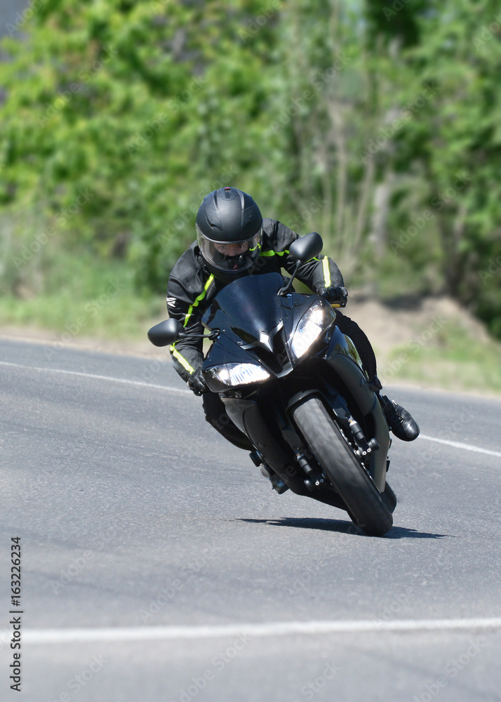 The biker on the black sports motorcycle on a bend on speed