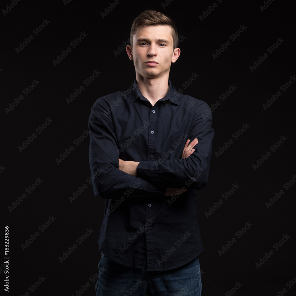 Young serious man portrait of a confident businessman showing presentation on a black background. Ideal for banners, registration forms, presentation, landings, presenting concept.