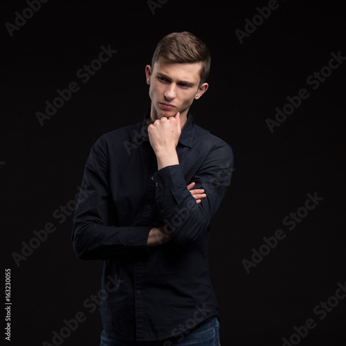 Young wistful man portrait of a confident businessman showing presentation on a black background. Ideal for banners, registration forms, presentation, landings, presenting concept.