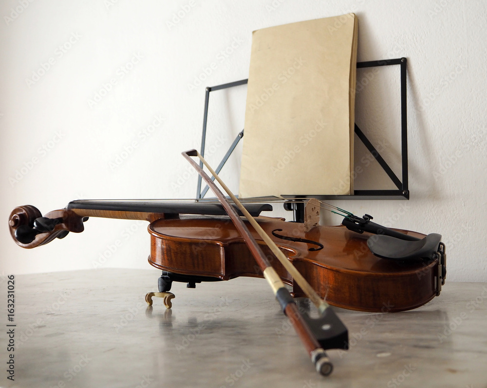 Violin and bow on marble table with a music stand on background Stock Photo | Stock