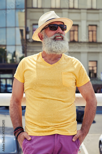 Stylish mature bearded man in bright yellow t-shirt and hat