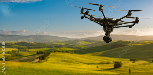 A flying drone with camera with blured hills of Tuscany in the background photo