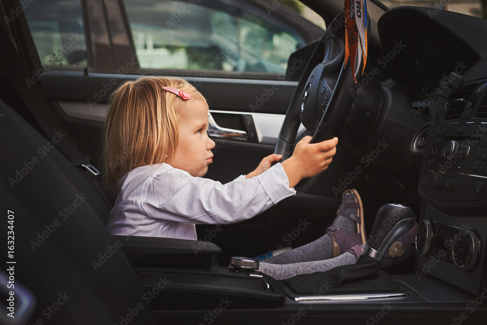 Маленькая девочка сидит за рулем автомобиля