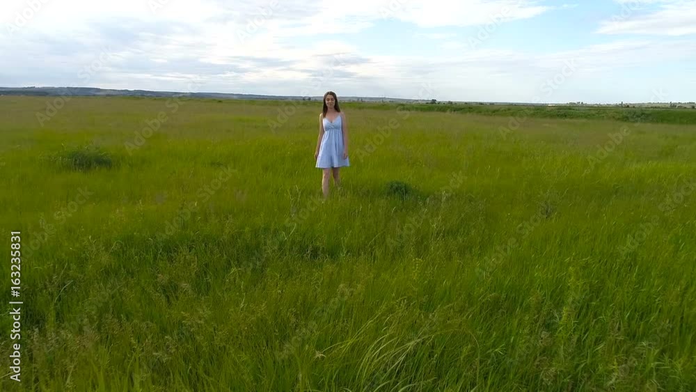 Young beautiful girl in dress goes on green field Young beautiful girl in dress goes on green field