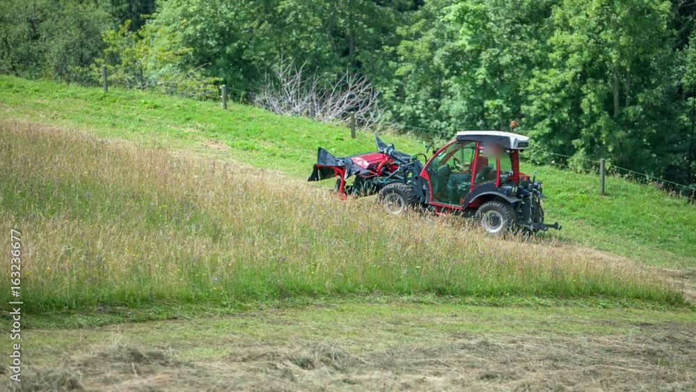 A red tractor is driving very fast uphill. The farmers are busy cutting grass during this time of the year. It is summer time. A red tractor is driving very fast uphill. The farmers are busy cutting grass during this time of the year. It is summer time.