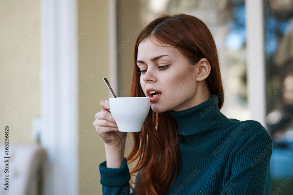 Beautiful young woman drinks coffee in a cafe on the street Beautiful young woman drinks coffee in a cafe on the street