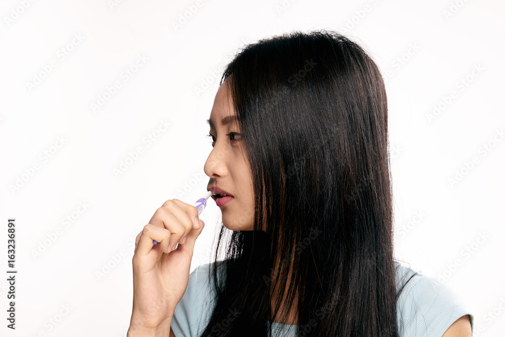 Beautiful young woman on white isolated background brushes teeth, asian Beautiful young woman on white isolated background brushes teeth, asian