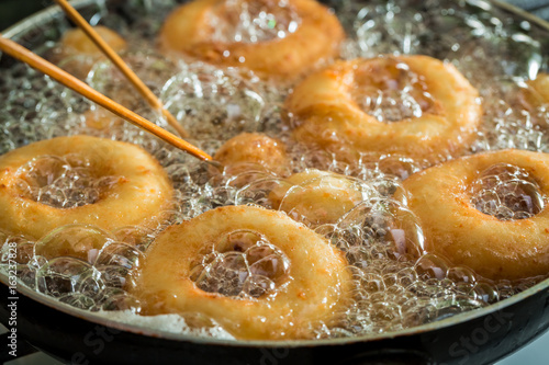 Frying sweet and tasty donuts on fresh oil