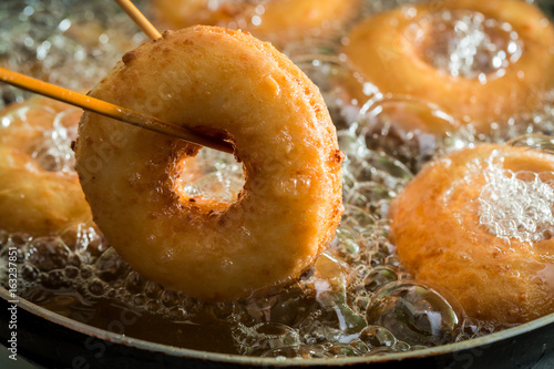 Frying homemade and sweet donuts on fresh oil