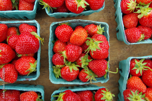Strawberries displayed in baskets for market on wooden table