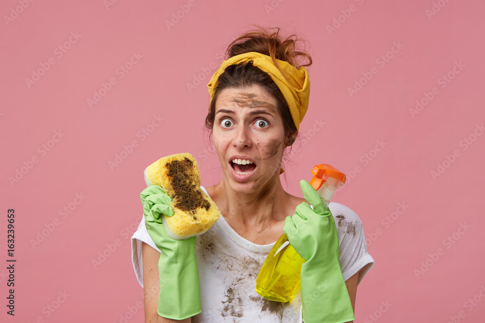 Headshot of dirty housemaid doing spring cleaning wearing rubber protective  gloves and headband on head looking with irritated and surprised look  hating dust and cleaning. Domestic work and chores Stock Photo