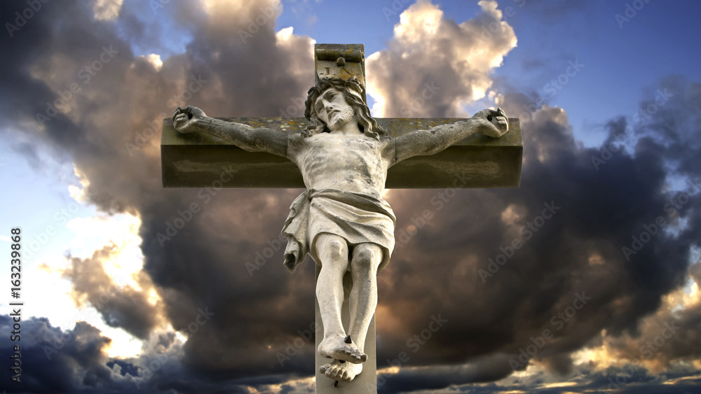 stone cross with Jesus and cloudy sky stone cross with Jesus and cloudy sky