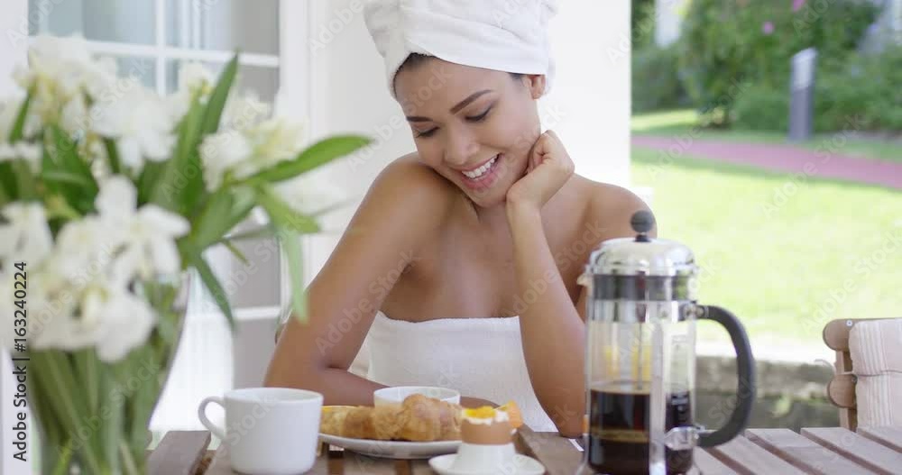 Playful young woman holding oranges to her eyes as she sits on an outdoor patio enjoying breakfast and laughing at the camera Playful young woman holding oranges to her eyes as she sits on an outdoor patio enjoying breakfast and laughing at the camera