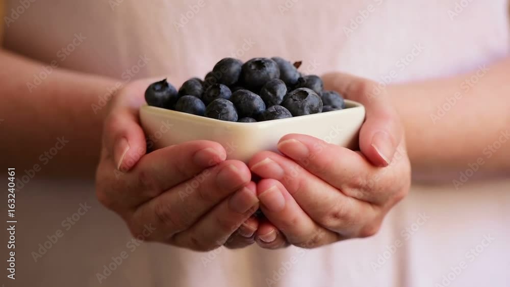 Woman offering blueberries in crockery, fresh ripe organic berry fruit Woman offering blueberries in crockery, fresh ripe organic berry fruit