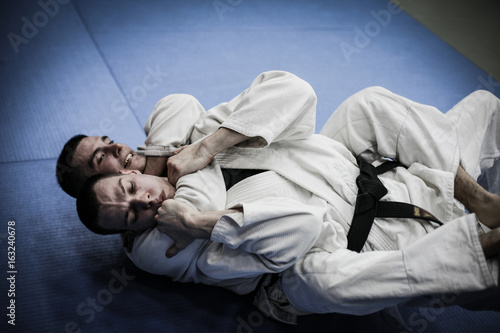 Two young males practicing judo together.