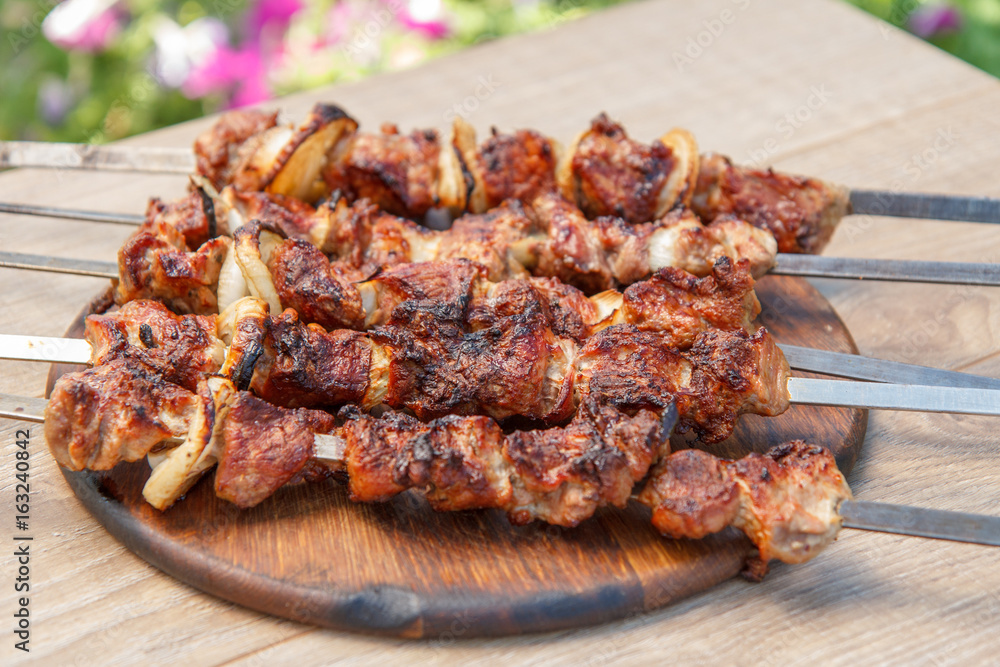 Grilled pork on skewers roasted on the grill on wooden chopping board Grilled pork on skewers roasted on the grill on wooden chopping board