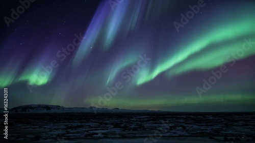 Strong bright Aurora Borealis snow covered lava field mountains Thingvellir Iceland realistic movement 4k photo