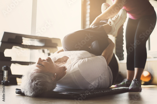 Senior woman workout in rehabilitation center. Personal trainer helping senior woman to do stretching exercise.