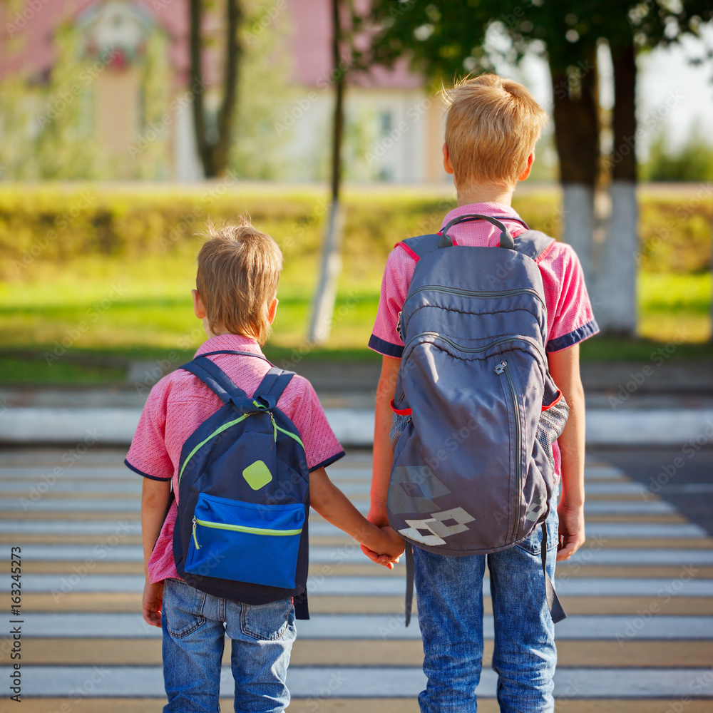 Two kids with backpacks walking on the road, holding. School time Stock ...