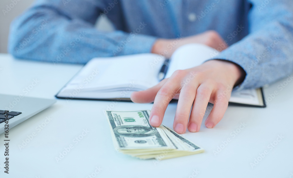 Man offering batch of hundred dollar bills. Hand giving money - United States Dollars (or USD). Hand receiving money from businessman. Selective focus. Venality, bribe, corruption concept. Man offering batch of hundred dollar bills. Hand giving money - United States Dollars (or USD). Hand receiving money from businessman. Selective focus. Venality, bribe, corruption concept.