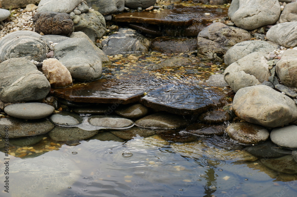 A small stone waterfall with several rapids and clear transparent spring water A small stone waterfall with several rapids and clear transparent spring water