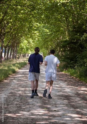 Two young men jogging in Vincennes forest of Paris, (France). Vincennes forest is the largest park of Paris.